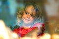 Beautiful little girl looks in the window of a shop in OIA, and makes funny faces Royalty Free Stock Photo