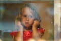 Beautiful little girl looks in the window of a shop in OIA, and makes funny faces Royalty Free Stock Photo