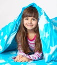 Beautiful little girl lying in bed under a blue blanket Royalty Free Stock Photo