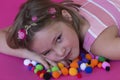 Beautiful little girl lying down on colorful pom poms