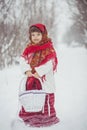 Beautiful little girl in old Russian clothes in a winter forest with wicker basket Royalty Free Stock Photo