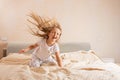 Beautiful little girl in pajamas jumping on the bed at home. Stay at home during coronavirus covid-19 lockdown and have Royalty Free Stock Photo