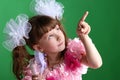 Beautiful little girl in a pink dress and with a glass in which a butterfly, points her finger up Royalty Free Stock Photo