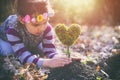 Beautiful little girl planting a heart-shaped tree and dreaming of a beautiful future Royalty Free Stock Photo