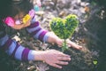 Beautiful little girl planting a heart-shaped tree and dreaming of a beautiful future Royalty Free Stock Photo