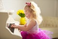 Beautiful little girl is playing on a white grand piano. Royalty Free Stock Photo