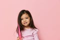 a beautiful little girl of preschool age stands on a pink background in a pink T-shirt and looks thoughtfully away Royalty Free Stock Photo