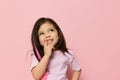 a beautiful little girl of preschool age stands on a pink background in a pink T-shirt and looks thoughtfully away Royalty Free Stock Photo