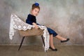 Beautiful little girl princess in blue dress sitting on white chair. Royalty Free Stock Photo