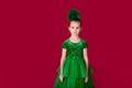 Beautiful little girl princess dancing in luxury green dress isolated on red background. Carnival party with costumes Royalty Free Stock Photo