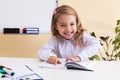 Beautiful little girl reads sitting at table Royalty Free Stock Photo