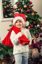 Beautiful little girl with santa claus hat and gift bag standing beside christmass tree Royalty Free Stock Photo