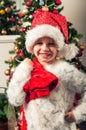 Beautiful little girl with santa claus hat and gift bag standing beside christmass tree Royalty Free Stock Photo