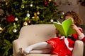 Beautiful little girl sits on the chair next to a nicely decorated Christmas tree Royalty Free Stock Photo