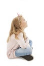 Beautiful little girl sitting on floor, looking on copy space