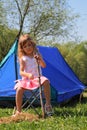 Beautiful little girl sitting near tent
