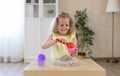 Beautiful little girl sitting at the table and playing with kinetic sand and a shovel. Royalty Free Stock Photo