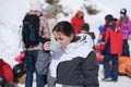 Beautiful little girl in ski suit drinking hot cup of tea on group of tourists people on winter alpine snow resort leisure Royalty Free Stock Photo