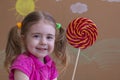 Beautiful little girl smiles with lollipop, happy little girl eating big sugar lollipop. Royalty Free Stock Photo