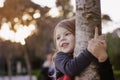 Beautiful little girl smiling, hugging a tree trunk. Little girl Royalty Free Stock Photo