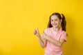 Beautiful little girl smiling joyfully and looking happy, feeling carefree and positive, holding both thumbs up