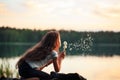 Pretty little girl is smiling in the park with dandelion flower. Happy cute kid having fun outdoors at sunset Royalty Free Stock Photo