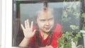 Beautiful little girl smiling and watching out the window. A child looks out the window. Portrait of cheerful kid. self Royalty Free Stock Photo