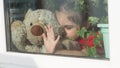 Beautiful little girl smiling and watching out the window. A child looks out the window. Portrait of cheerful kid. self Royalty Free Stock Photo