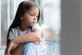 Beautiful little girl watching out the window. Young girl looking from window. Cheerful kid lies at windowsill Royalty Free Stock Photo