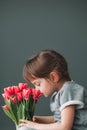 Beautiful little girl sniffing pink tulips