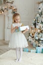 Beautiful little girl standing near Christmas tree and looking f