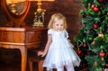 Beautiful little girl stands and smiles near festive tree Royalty Free Stock Photo