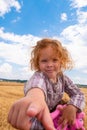 Beautiful little girl sticks her finger into the camera against the background of blue sky and white clouds Royalty Free Stock Photo