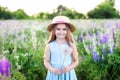 Beautiful little girl in a straw hat and dress holds a dandelion in a flowering field. Nature concept. A smiling girl is playing o Royalty Free Stock Photo