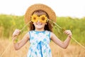 Beautiful little girl in straw hat with fluttering hair hide eye with sunflower flower, walking outdoor in summer Royalty Free Stock Photo