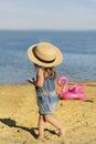 Beautiful little girl in a straw hat on a sandy beach against the sea Royalty Free Stock Photo
