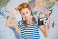 Beautiful little girl in striped sailor shirt and sunglasses with vintage camere in hand on world map background Royalty Free Stock Photo
