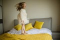 Beautiful little girl in stylish dress jumping on the bed with white blanket at home. Stay at home during coronavirus Royalty Free Stock Photo