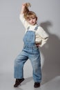 Beautiful little girl wearing stylish denim overall, white roll neck fluffy jumper posing on white background Royalty Free Stock Photo