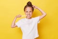 Beautiful little girl with wet hair wearing casual white T-shirt standing isolated over yellow background brushing her teeth while Royalty Free Stock Photo