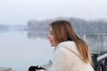 Beautiful little girl in white coat looking at the river, surprised Royalty Free Stock Photo