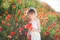 Beautiful little caucasian girl in white dress holding poppy red in green summer field Royalty Free Stock Photo