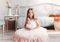 Beautiful little girl in white dress sits on the floor in a light room. Looking at camera. Childhood Royalty Free Stock Photo