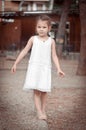 Beautiful little girl in a white dress walking barefoot on a log Royalty Free Stock Photo