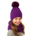 Beautiful little girl in winter warm purple hat and scarf on white. Children winter clothes