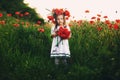 Beautiful little girl with a wreath of poppies in a white dress and a bouquet of wildflowers. cute child in poppy field Royalty Free Stock Photo