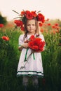 Beautiful little girl with a wreath of poppies in a white dress and a bouquet of wildflowers. cute child in poppy field Royalty Free Stock Photo