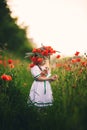 Beautiful little girl with a wreath of poppies in a white dress and collects a bouquet of wildflowers. cute child in poppy field Royalty Free Stock Photo