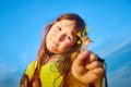 Beautiful little girl in yellow dress with red strawberries in the field with green grass, yellow flowers and blue sky Royalty Free Stock Photo