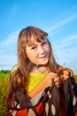 Beautiful little girl in yellow dress with red strawberries in the field with green grass, yellow flowers and blue sky Royalty Free Stock Photo